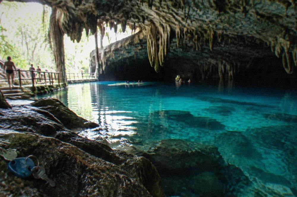 Clear turquoise water in a limestone cavern cenote with stalactites above the surface