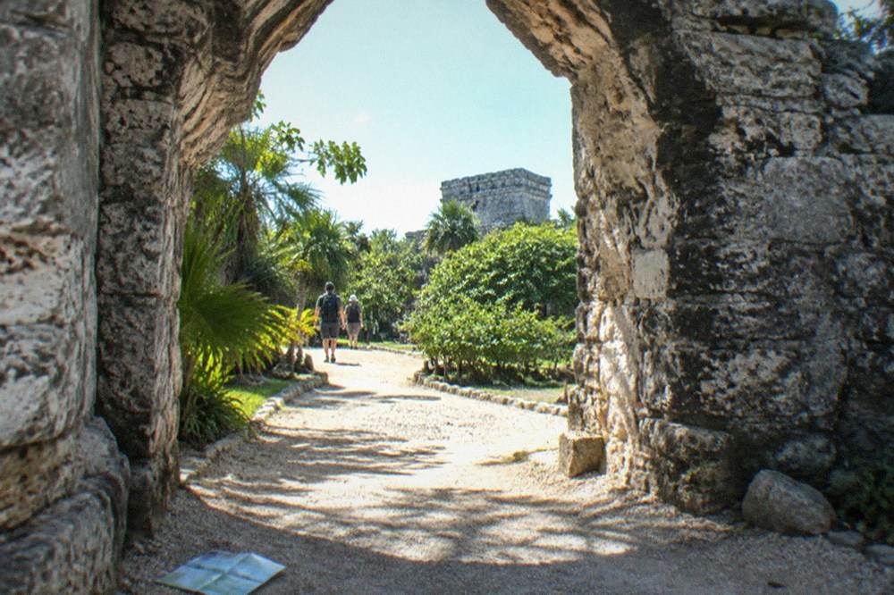 Sunlit stone archway of an ancient ruin with calm green jungle foliage around it