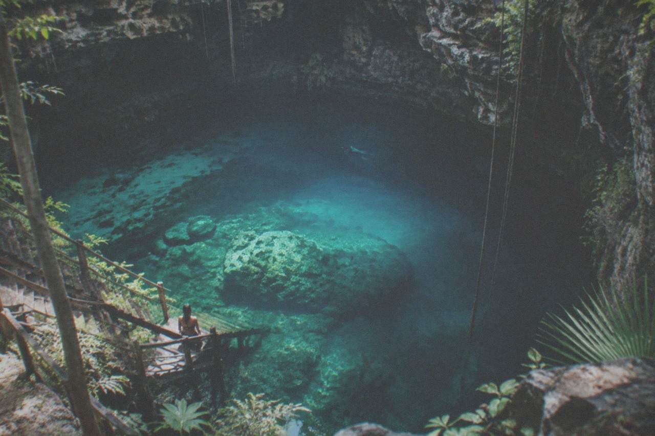 Clear turquoise water filling a limestone sinkhole with rock walls and submerged cave formations