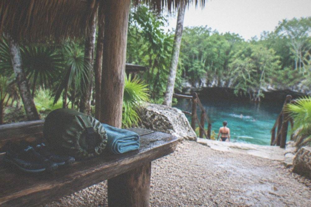 Water shoes, a dry bag and a quick-dry towel packed on a wooden bench
