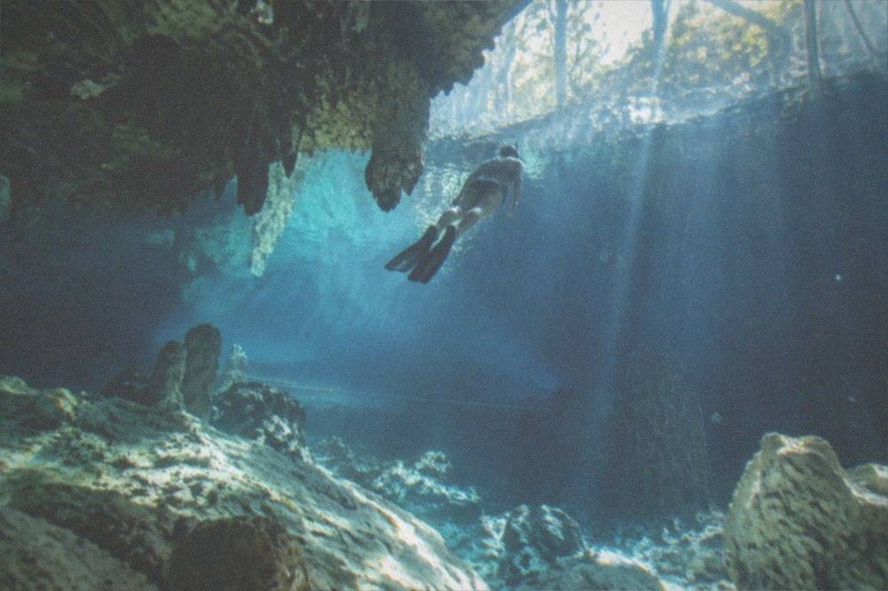 Snorkeler floating above pale limestone formations in deep clear water