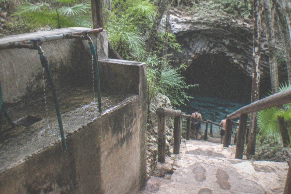 Rinse station and wooden stairs leading down to a cavern entrance in the jungle
