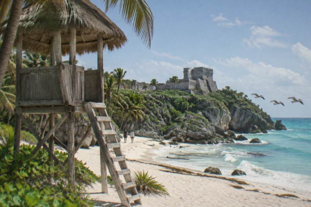 Wooden lifeguard lookout tower on an empty sand beach under palm trees