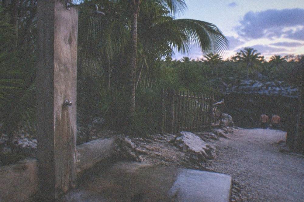 A rinse station with a shower head and a sign at a cenote entrance